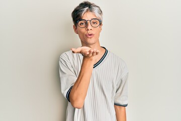 Young hispanic man wearing casual clothes and glasses looking at the camera blowing a kiss with...