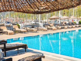 view through umbrella of sun-chair to water pol and yachts in marine