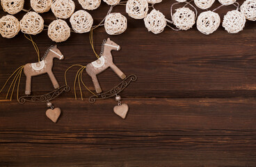 Christmas wooden toys rocking horse, a garland of natural material on a dark wooden background. New Year concept. Top view. Copy space