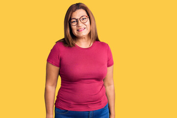 Middle age latin woman wearing casual clothes and glasses looking positive and happy standing and smiling with a confident smile showing teeth