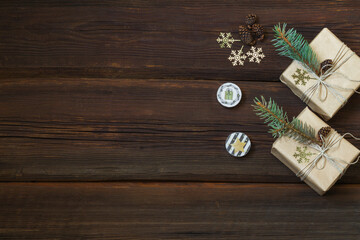 Fototapeta na wymiar Handmade christmas gift boxes decorated with craft paper, golden snowflakes, pine cones on a dark wooden background from above. Greeting card. Winter new year theme. Copy space.