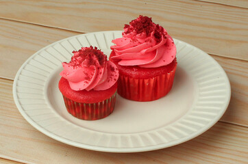 Red velvet cupcakes with cream cheese icing on white plate for birthday celebration