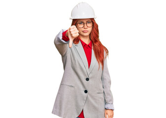 Young redhead woman wearing architect hardhat looking unhappy and angry showing rejection and negative with thumbs down gesture. bad expression.