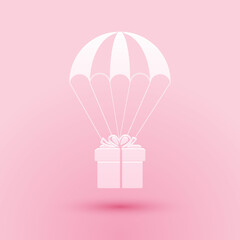 Paper cut Gift box flying on parachute icon isolated on pink background. Delivery service, air shipping concept, bonus concept. Paper art style. Vector.