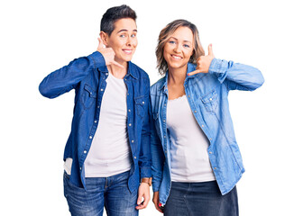 Fototapeta premium Couple of women wearing casual clothes smiling doing phone gesture with hand and fingers like talking on the telephone. communicating concepts.