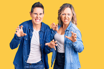 Couple of women wearing casual clothes smiling funny doing claw gesture as cat, aggressive and sexy...