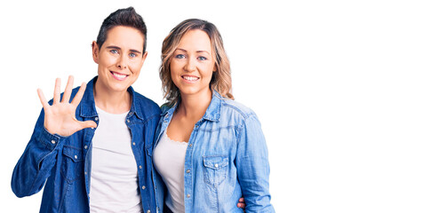 Obraz premium Couple of women wearing casual clothes showing and pointing up with fingers number five while smiling confident and happy.
