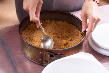 Placing the crushed biscuit in the baking dish.