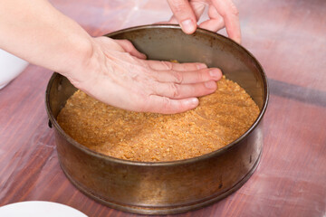 Placing the crushed biscuit in the baking dish.