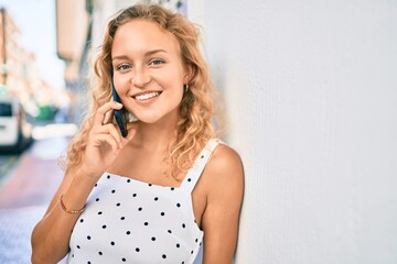 Fototapeta premium Young beautiful caucasian woman with blond hair smiling happy outdoors speaking on the phone