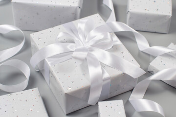 Wrapped grey Gift boxes with white ribbon on grey