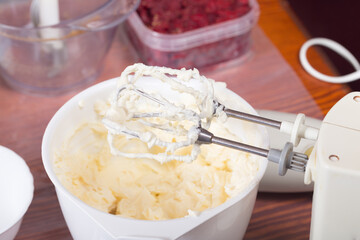 Whipping the cream with an electric mixer.