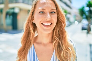 Young beautiful caucasian woman with blond hair smiling happy and cheerful walking on sunny day