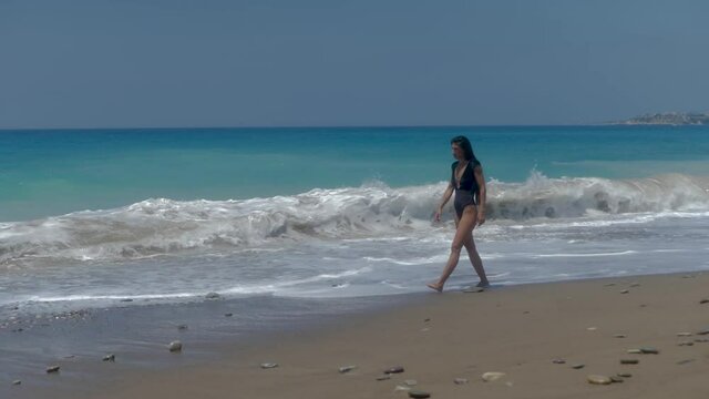 Lonely Female in Swimsuit Walking on a Sandy Beach by Waves of Mediterranean Sea on Summer Day, Full Frame