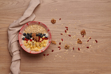 Healthy snacks in bowl: yoghurt, oat flakes, fruit, chia and goji seeds.