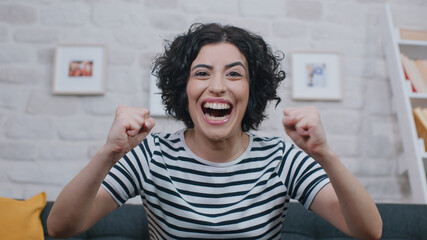Smiling young woman looking into the camera, wildly delighted with something. Portrait of beautiful...