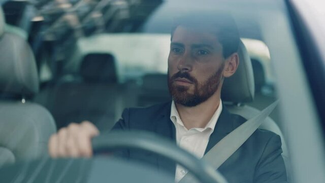 Successful wealthy businessman driving luxury car in the city center. Concentrated driver in moving car. Automobile, traveling, transportation. Business trip.