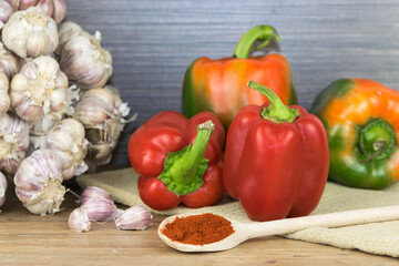 Natural, organic red pepper on wooden background with 
spice on a spoon and a bunch of garlic