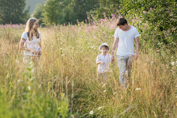 Naklejka na ściany i meble Happy family enjoying walk together at meadow in summer