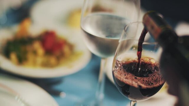 Red wine poured into a wine glass in a restaurant.