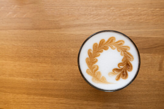 Latte foam art top view. Coffee latte in glass cup on brown table in cafe. Whipped cream design
