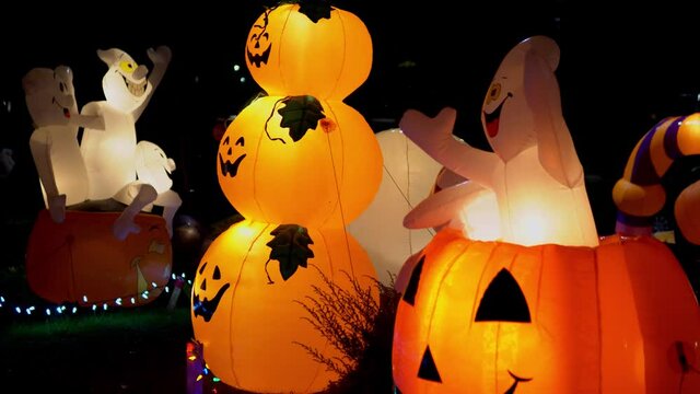 Two ghosts rise and fall in a inflatable pumpkin decoration at Halloween.