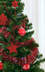 portion of Christmas tree with balls, festoons and decorations in red