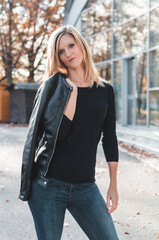 Portrait of attractive young caucasian blonde woman holding jacket with business building in background