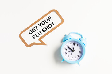 Text GET YOUR FLU SHOT isolated on white background with alarm clock.