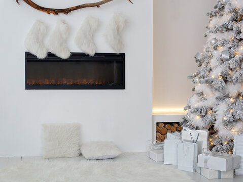 Fireplace with christmas stockings and gifts in interior of room. White fireplace is decorated with Christmas socks in living room. Empty stockings hung on fireplace on Xmas. Scandinavian interior	
