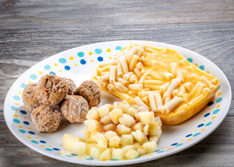 Frozen elements of a meatball TV dinner on a white plate