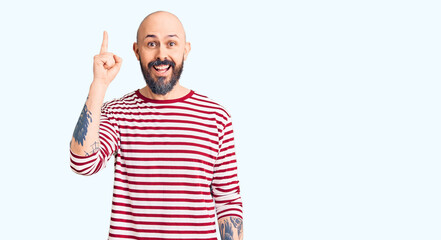 Naklejka premium Young handsome man wearing casual clothes pointing finger up with successful idea. exited and happy. number one.