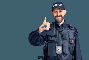 Obraz premium Young handsome man wearing police uniform doing happy thumbs up gesture with hand. approving expression looking at the camera showing success.