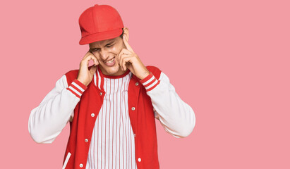 Handsome caucasian man wearing baseball uniform covering ears with fingers with annoyed expression for the noise of loud music. deaf concept.