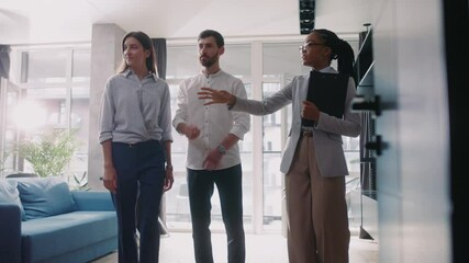 African american housing agent woman talking with positive beautiful couple discussing new apartment showing stylish rooms. Buying new house concept.