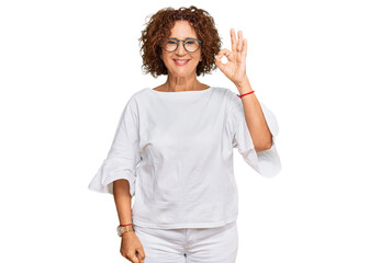 Beautiful middle age mature woman wearing casual clothes and glasses smiling positive doing ok sign with hand and fingers. successful expression.