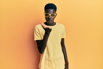 Young african american man wearing casual clothes and glasses looking at the camera blowing a kiss with hand on air being lovely and sexy. love expression.