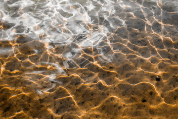 bottom, water ripples.Glare on the surface of the water are refracted and create a beautiful pattern on the bottom of the lake.