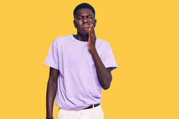 Young african american man wearing casual clothes touching mouth with hand with painful expression because of toothache or dental illness on teeth. dentist