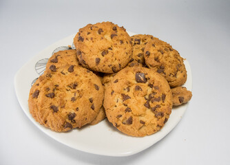 A closeup of freshly baked chocolate chip cookies on a saucer isolated on white background
