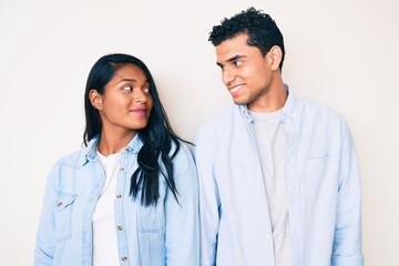 Beautiful latin young couple wearing casual clothes smiling looking to the side and staring away thinking.