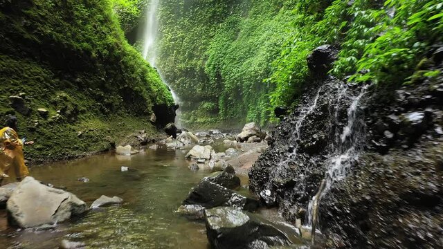 Cinematic low flypass of Madakaripura waterfall canyon along the stream, Java Island, Indonesia.
