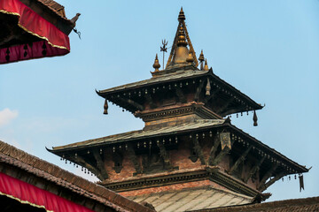 The rooftops of Durbar Square in Kathmandu, Nepal. There are plenty of pigeons flying around, and sitting on the rooftops. Each rooftop is ornated with red and golden ribbon. UNESCO heritage list.