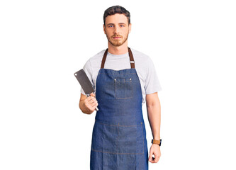 Handsome young man with bear wearing professional apron holding knife thinking attitude and sober expression looking self confident