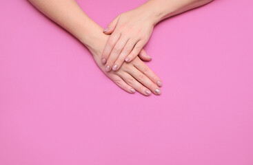 Women's hands with a beautiful delicate manicure on a colored background. View from above. A place for text.