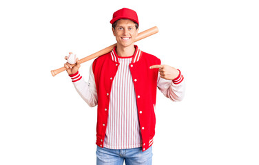 Young handsome man playing baseball holding bat and ball pointing finger to one self smiling happy and proud