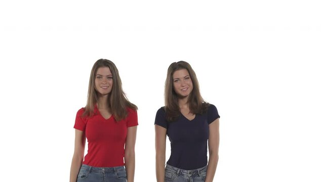 Caucasian twin sisters suddenly appearing from bottom on camera, smiling and spreading hands. Make surprise. Emotions concept. Isolated on white background