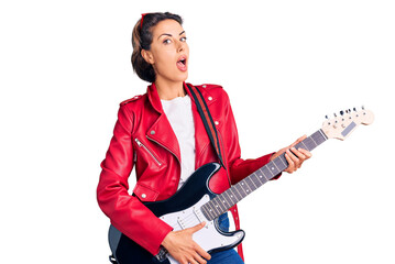 Fototapeta premium Young beautiful woman playing electric guitar scared and amazed with open mouth for surprise, disbelief face