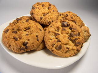 A closeup of freshly baked chocolate chip cookies on a saucer isolated on white background
