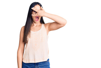 Young beautiful caucasian woman wearing casual clothes and glasses peeking in shock covering face and eyes with hand, looking through fingers with embarrassed expression.